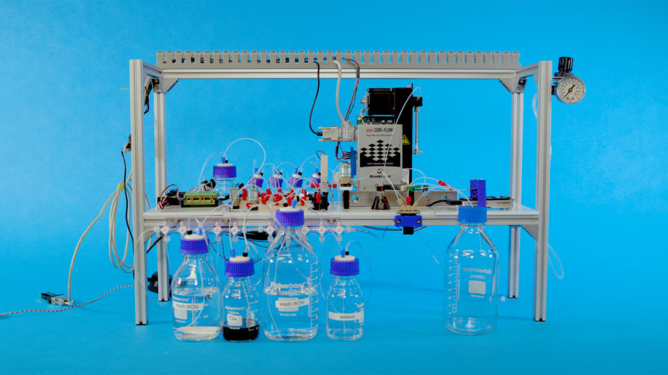The automated DNA data storage system in a metal frame, in front of glass beakers